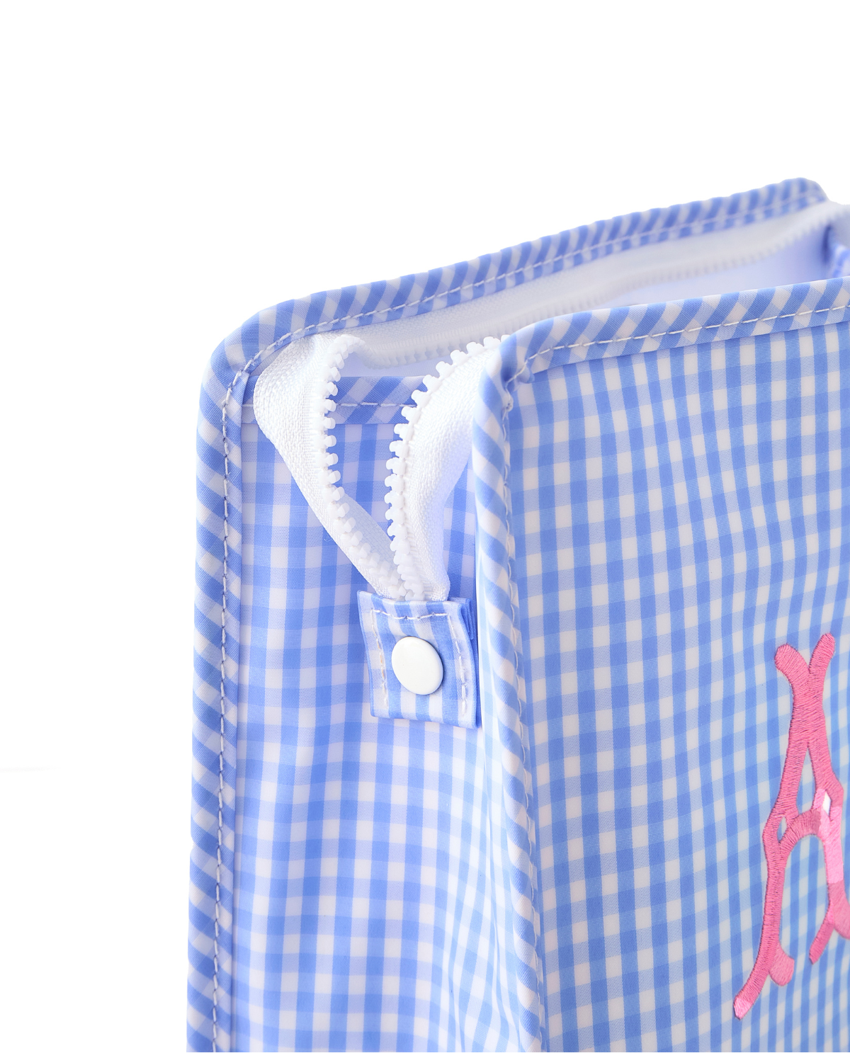 Close-up of a blue gingham pouch with pink monogram embroidery.