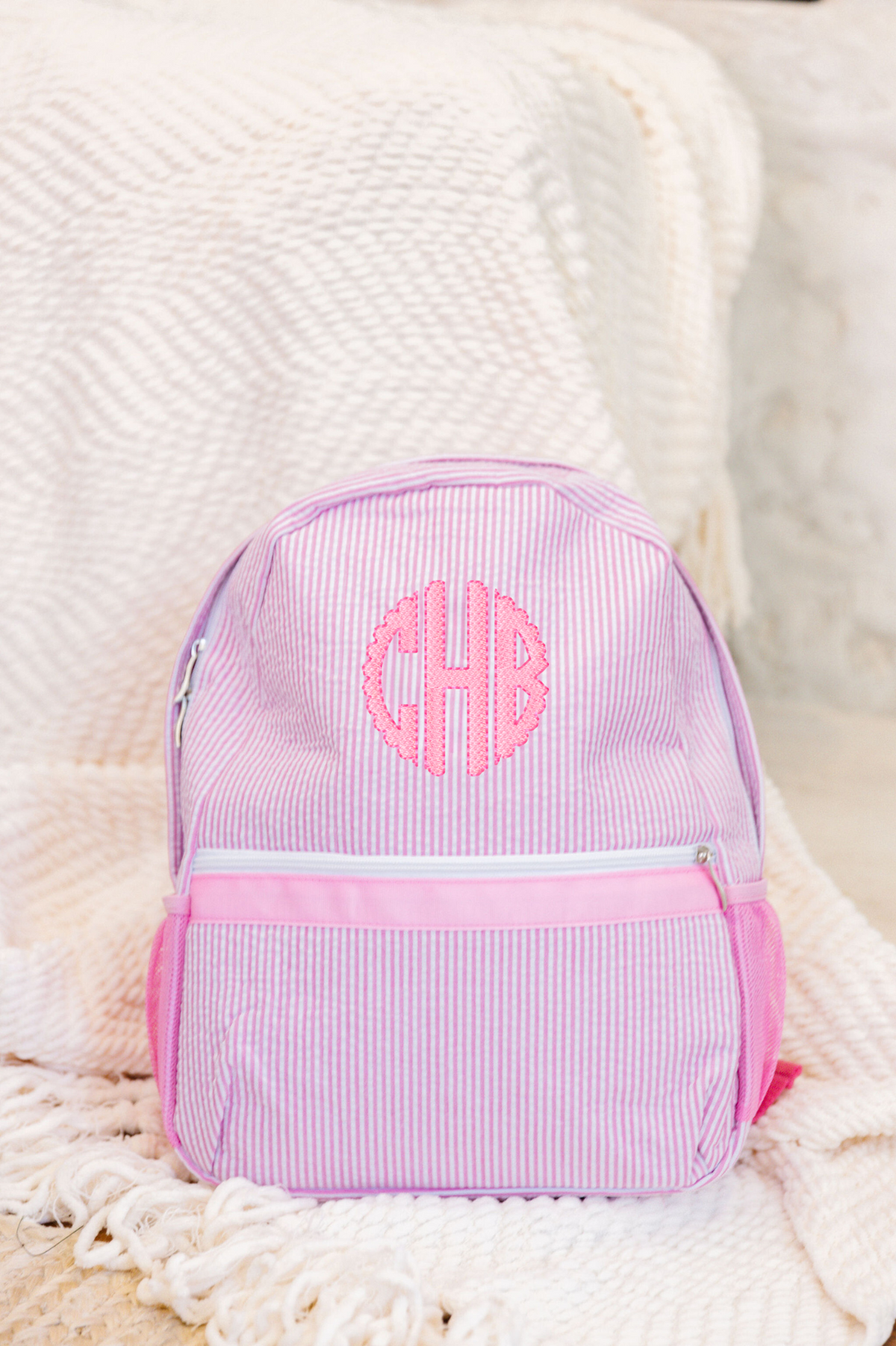 Pink striped backpack with a monogram 'CHB' embroidered in pink