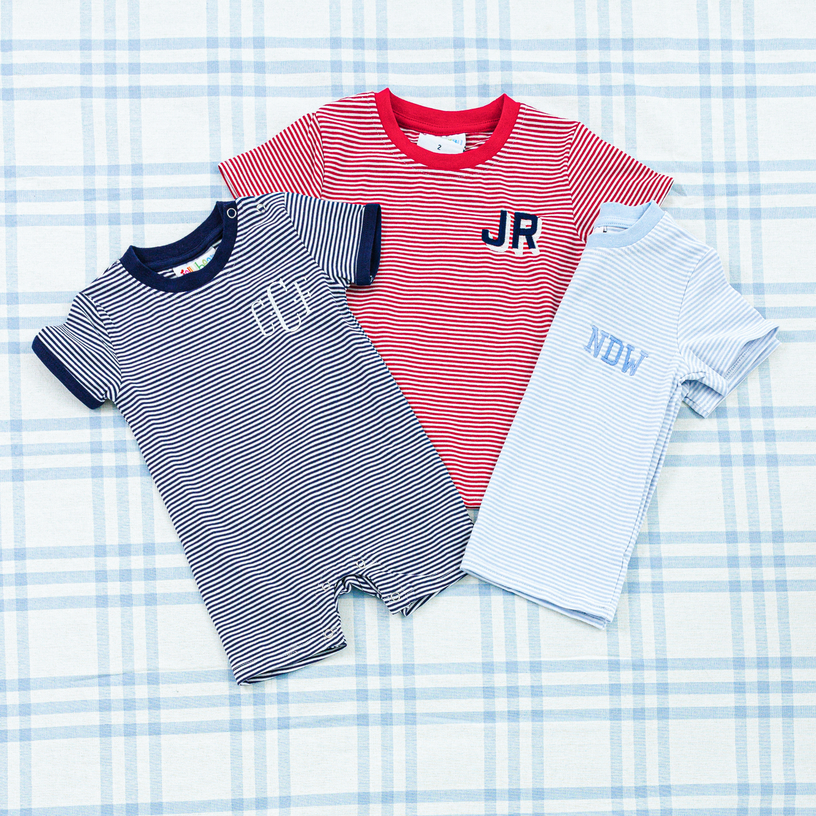Two personalized striped baby outfits: a navy romper and a light blue t-shirt 
