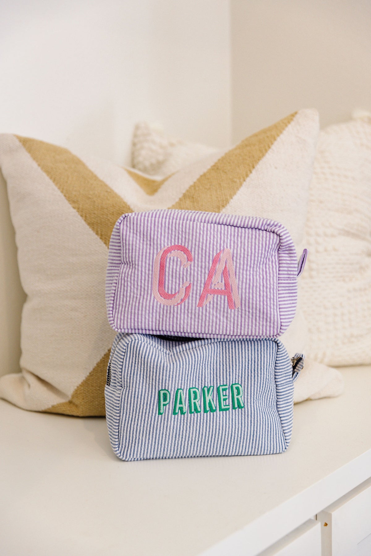 Two striped pouches, one in lavender and one in blue with embroidery.