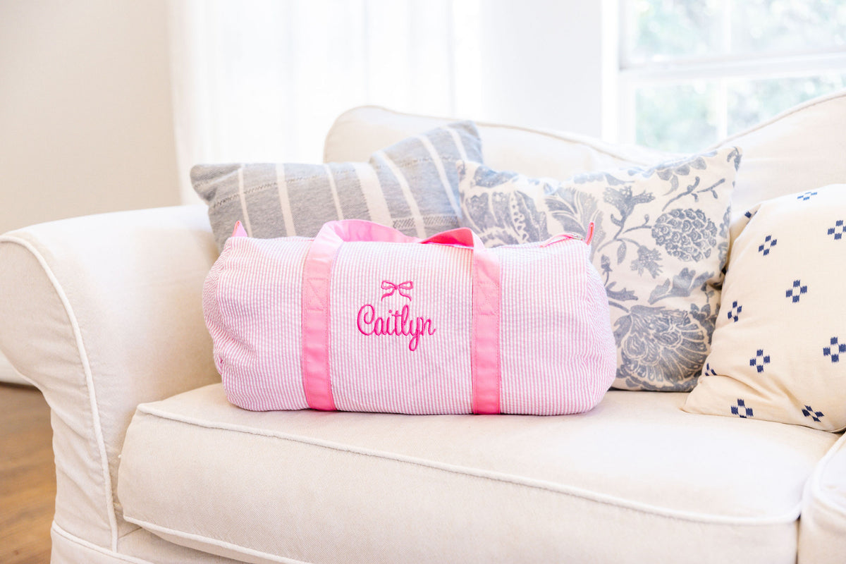 Pink striped duffel bag featuring matching pink handles.