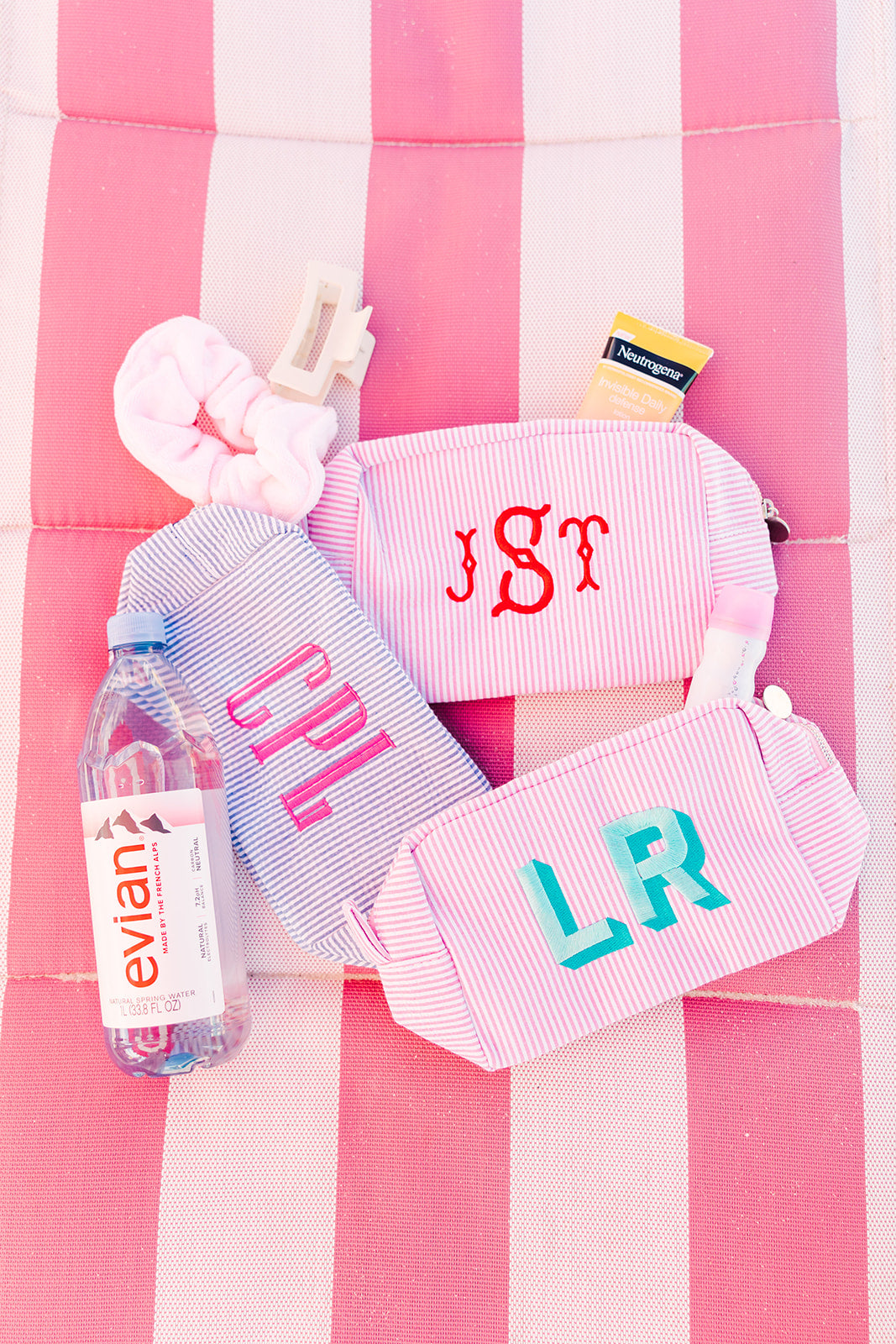 Three striped pouches, one in pink, one in blue and one in pink with monogram embroidered.