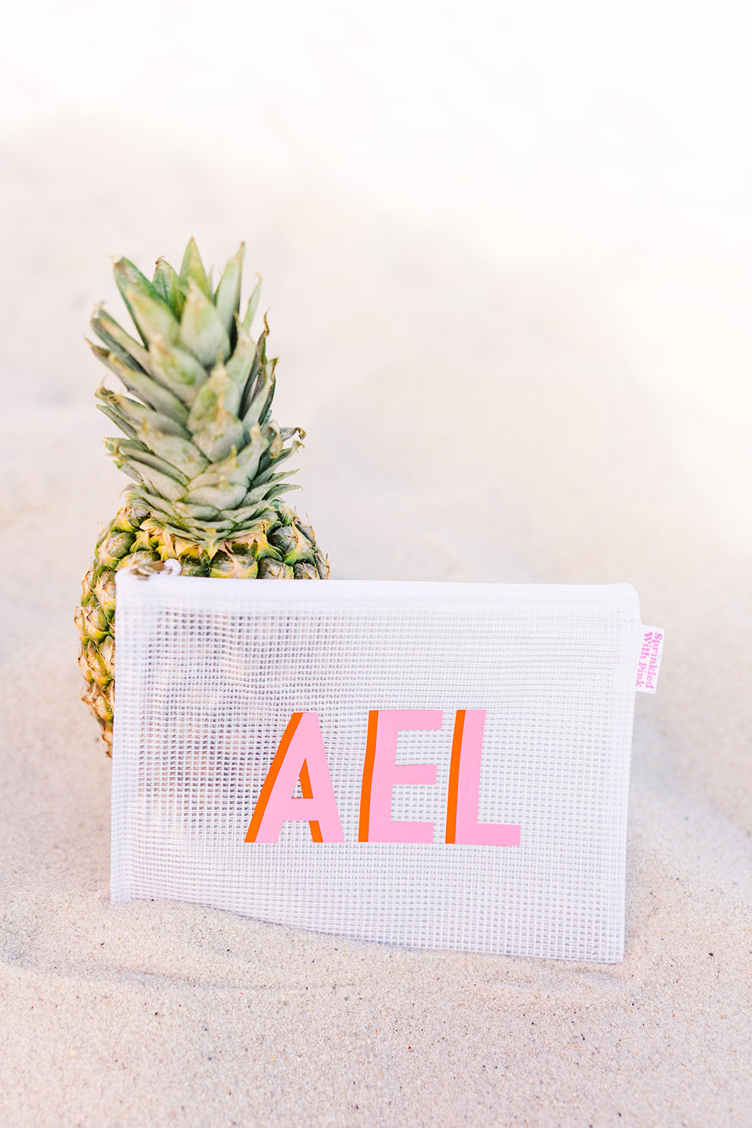 White mesh pool bag with pink trim, featuring bold, vibrant initials 
