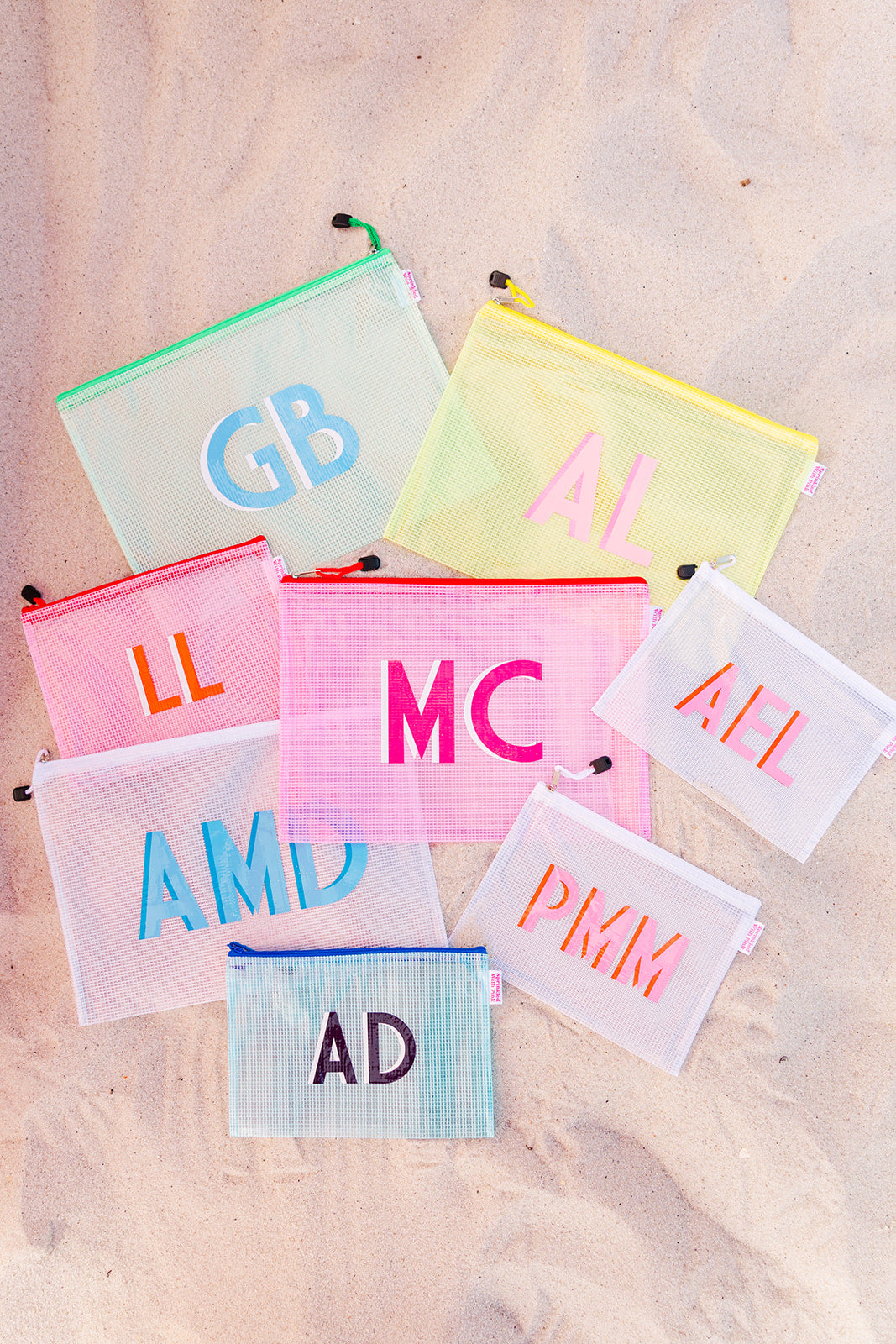 Eight clear pool bags with colorful zippers and monograms
