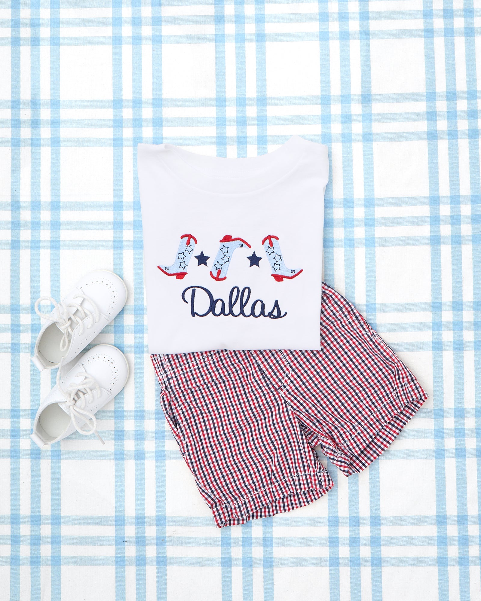 Striped Short Sleeve Romper & T-Shirt with Motif featuring patriotic embroidery—navy striped romper with fireworks, flag, hotdog, and the name “Barrett,” paired with a white tee showcasing two lab puppies holding a string of American flags and the name “Collins.”