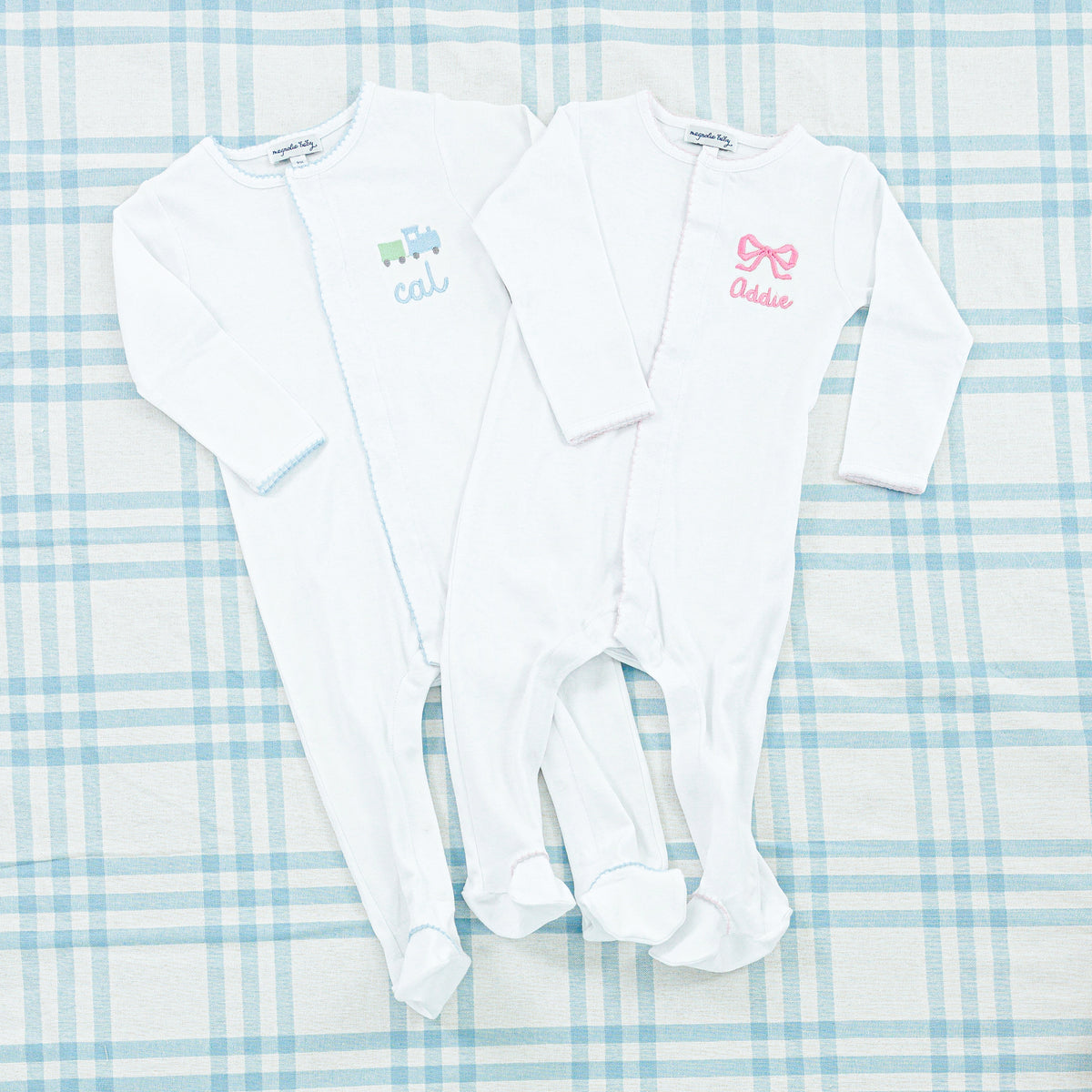 Two personalized baby onesies both in soft white fabric.