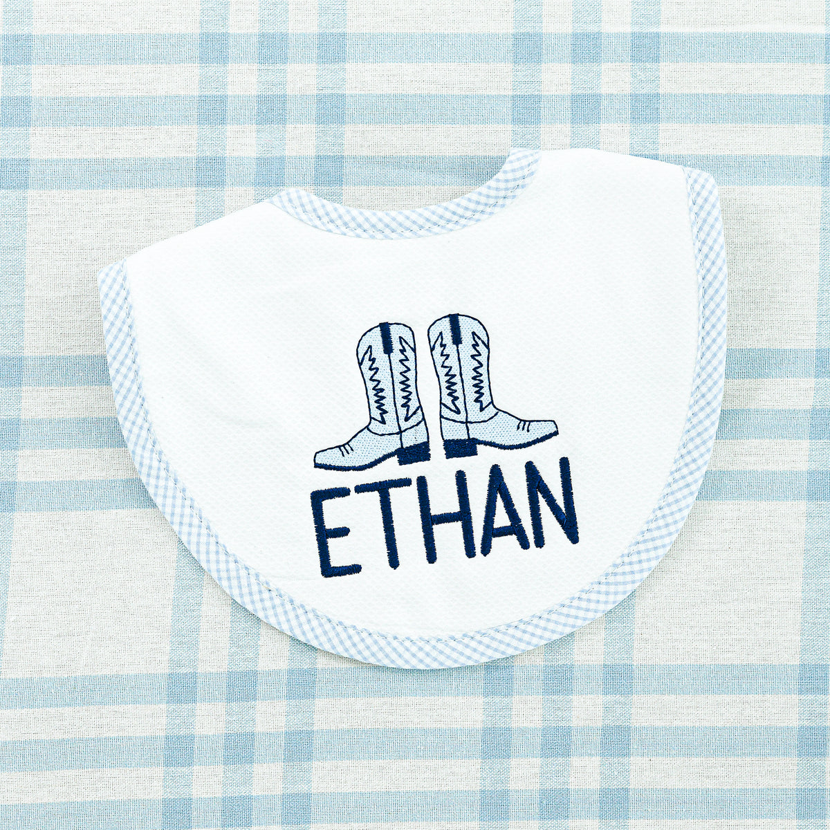 White bib with light blue trim featuring embroidered cowboy boots