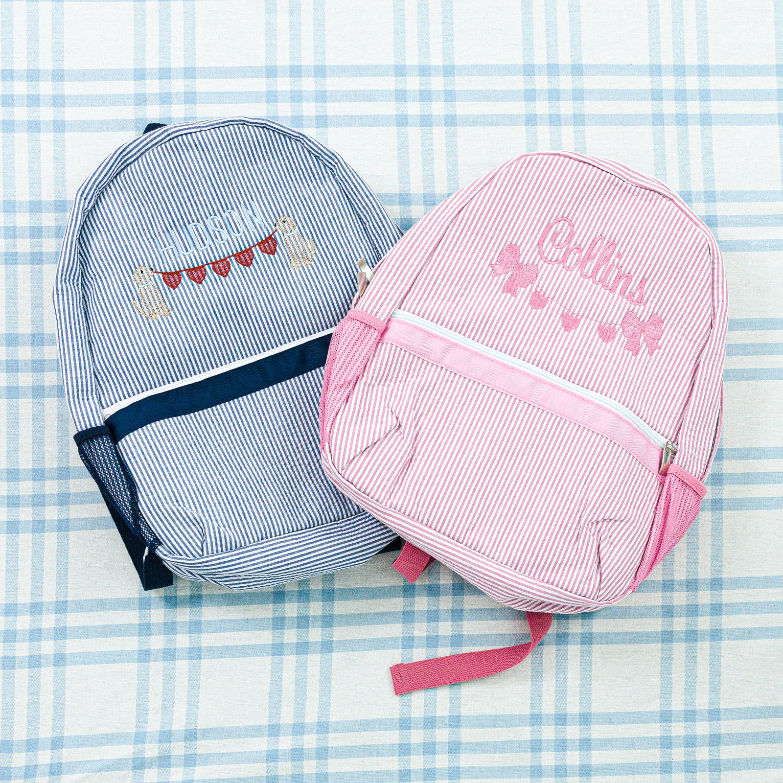 Two personalized seersucker backpacks: a pink backpack and a blue backpack.