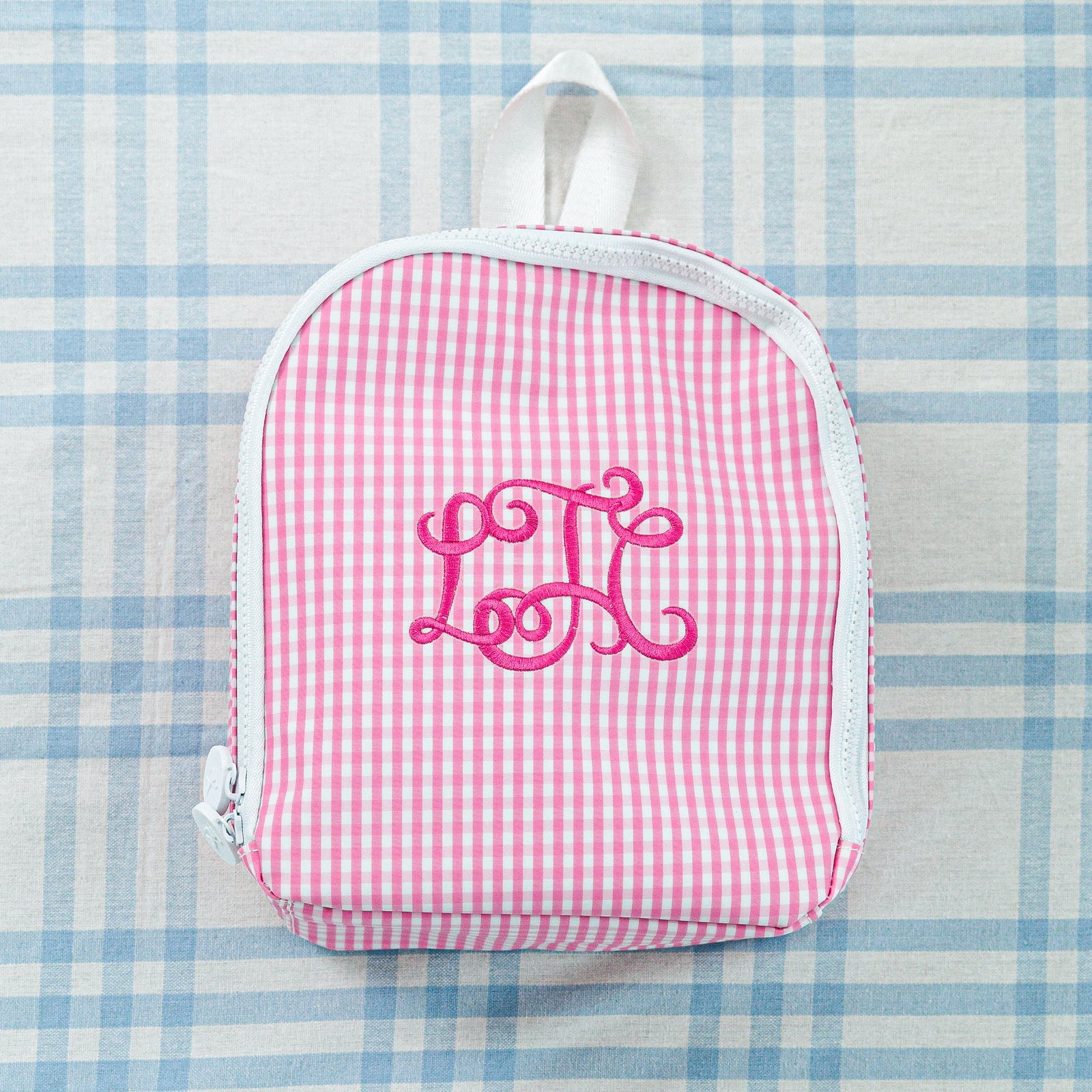 Two personalized children's bags: a blue-striped bag and a pink gingham bag with a bow design.
