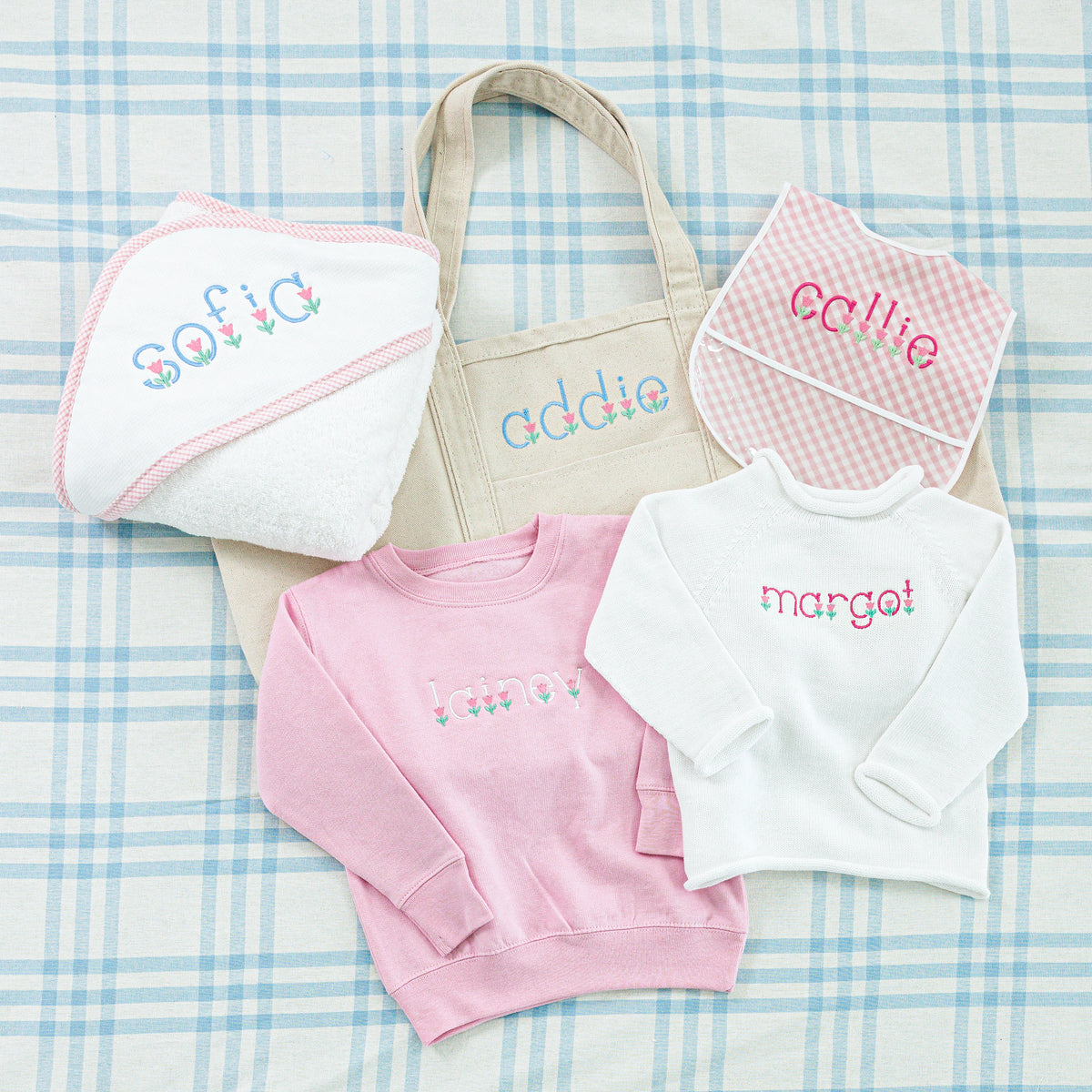 A personalized baby gift set embroidered in a matching floral-themed font.