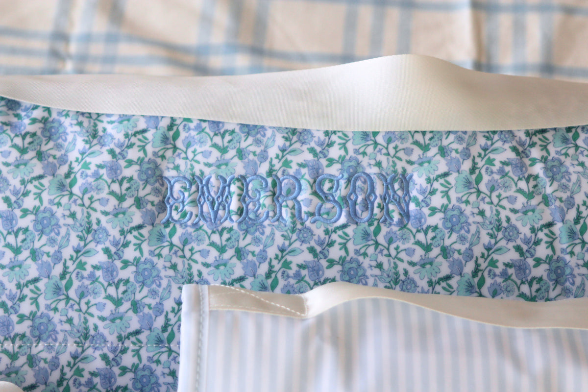 Close-up of a personalized Nap Mat embroidered with the name "Emerson" in light blue thread, featuring a delicate blue and green floral print. This cozy and stylish nap mat is perfect for daycare or preschool rest time.