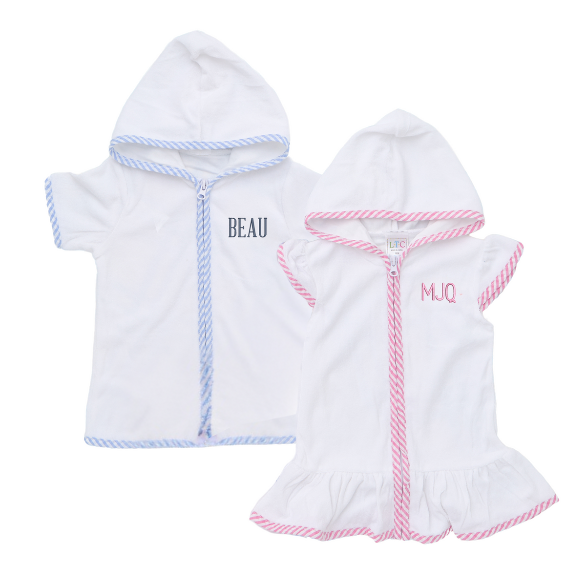 Two Kid's Terry Towel Robes with hoods are displayed side by side—one with blue striped trim and the name "Beau" embroidered in a bold navy font, and the other with pink striped trim, ruffled hem, and the monogram "MJQ" stitched in soft pink. These lightweight robes are made from plush terry cloth, featuring short sleeves, zip-up fronts, and personalized embroidery, perfect for beach days, poolside drying, or cozy bath time.