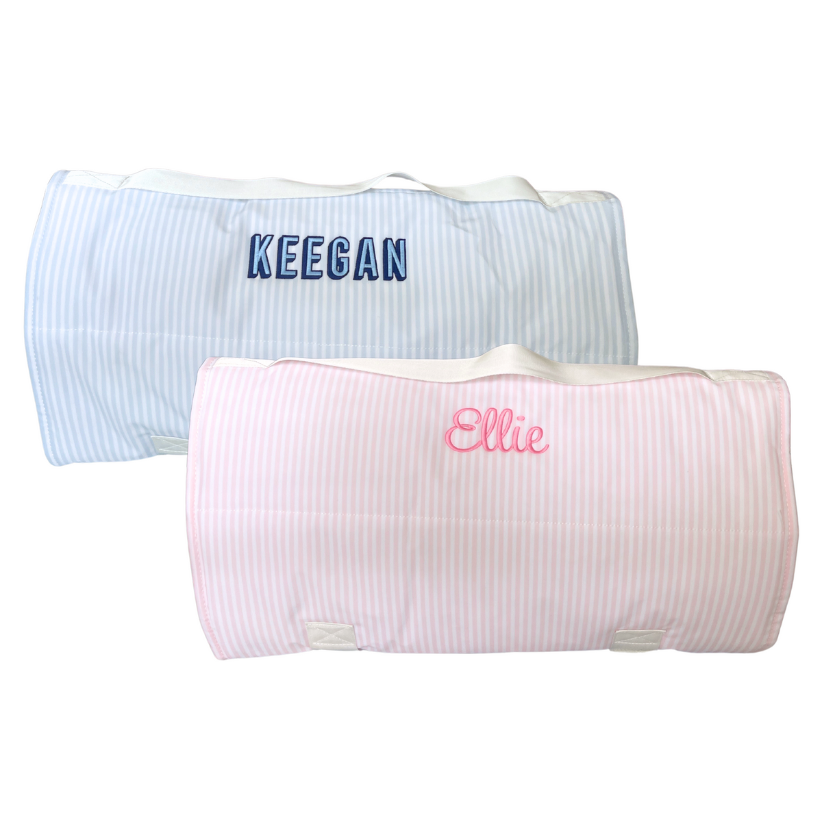 Rolled-up Nap Mats in pastel stripes, featuring one light blue mat with "Keegan" embroidered in bold navy lettering and one pink mat with "Ellie" embroidered in bright pink script. These personalized Nap Mats are perfect for daycare, preschool, or travel, offering a soft and cozy resting solution with convenient carry handles.