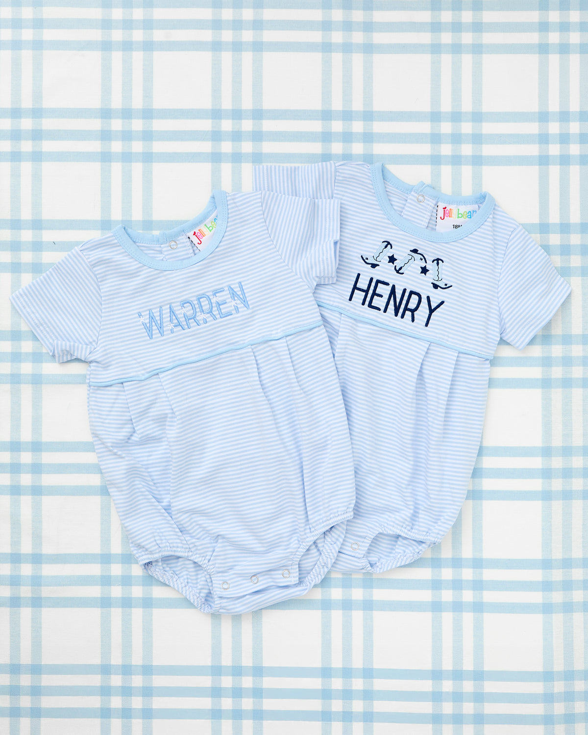 Two baby blue short sleeve striped bubbles with snap closures, personalized with names "Warren" and "Henry," and featuring playful embroidery including text and dancing boot motifs—perfect for a cute and custom baby look.