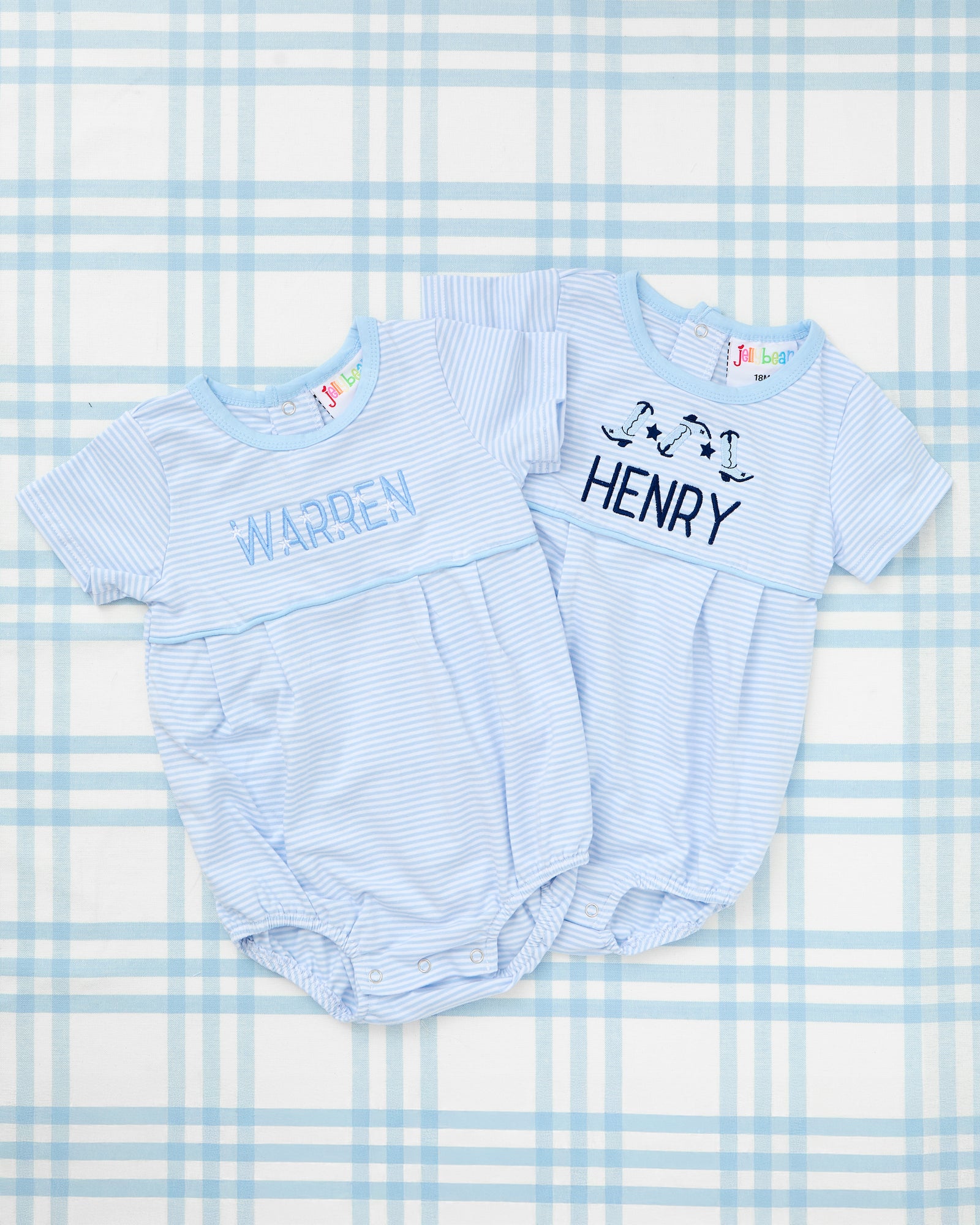 Image of a light blue Short Sleeve Striped Bubble with Motif, featuring delicate horizontal pinstripes and a soft round neckline. The bubble is personalized with the name "WALKER" in bold navy embroidery, flanked by two charming embroidered tan puppy motifs on either side. Perfectly designed for everyday comfort and personalized charm.