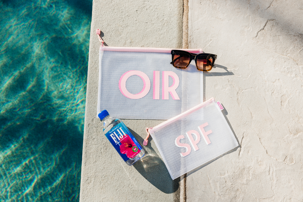 Two clear pouches with pink zippers and monograms in different sizes.