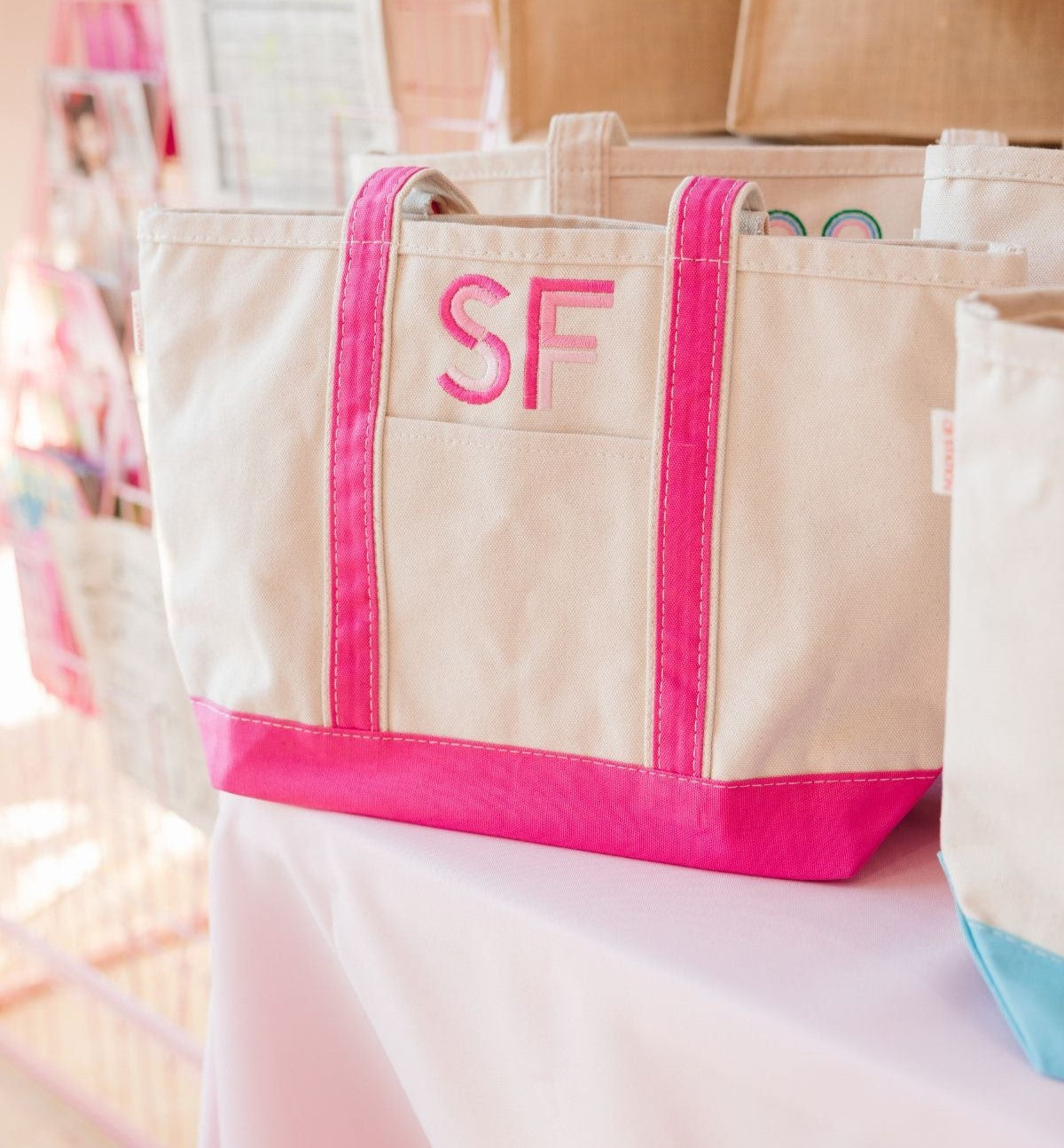  A beige canvas tote bag featuring bold pink handles and a matching pink bottom.