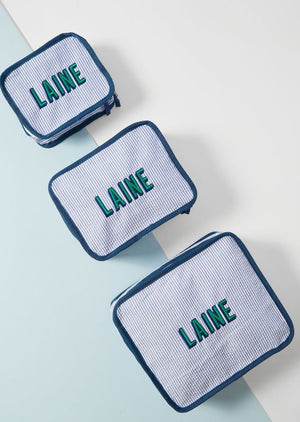 Three blue striped pouches with navy trim, all monogrammed 