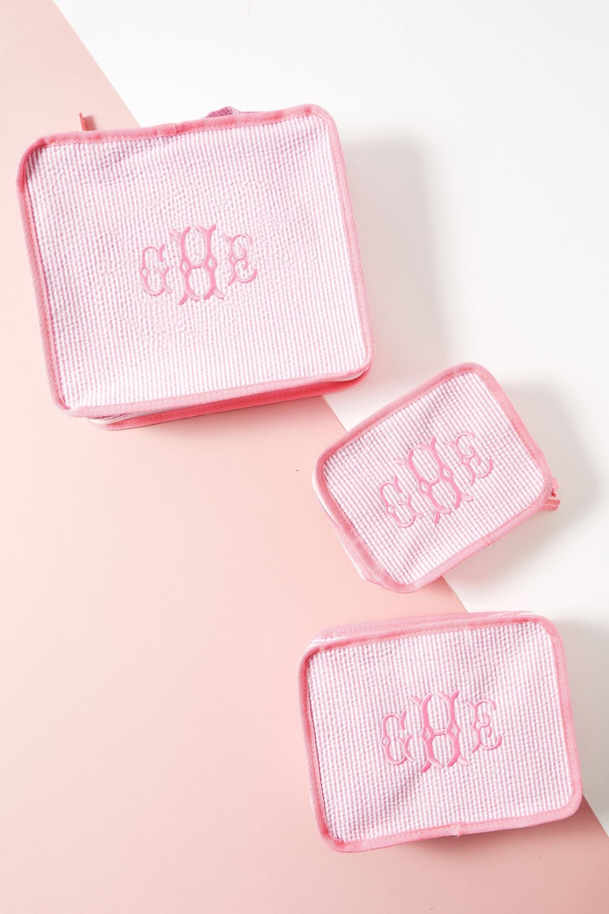 Three pink striped pouches with matching pink trim, all monogrammed with 'CBE' 