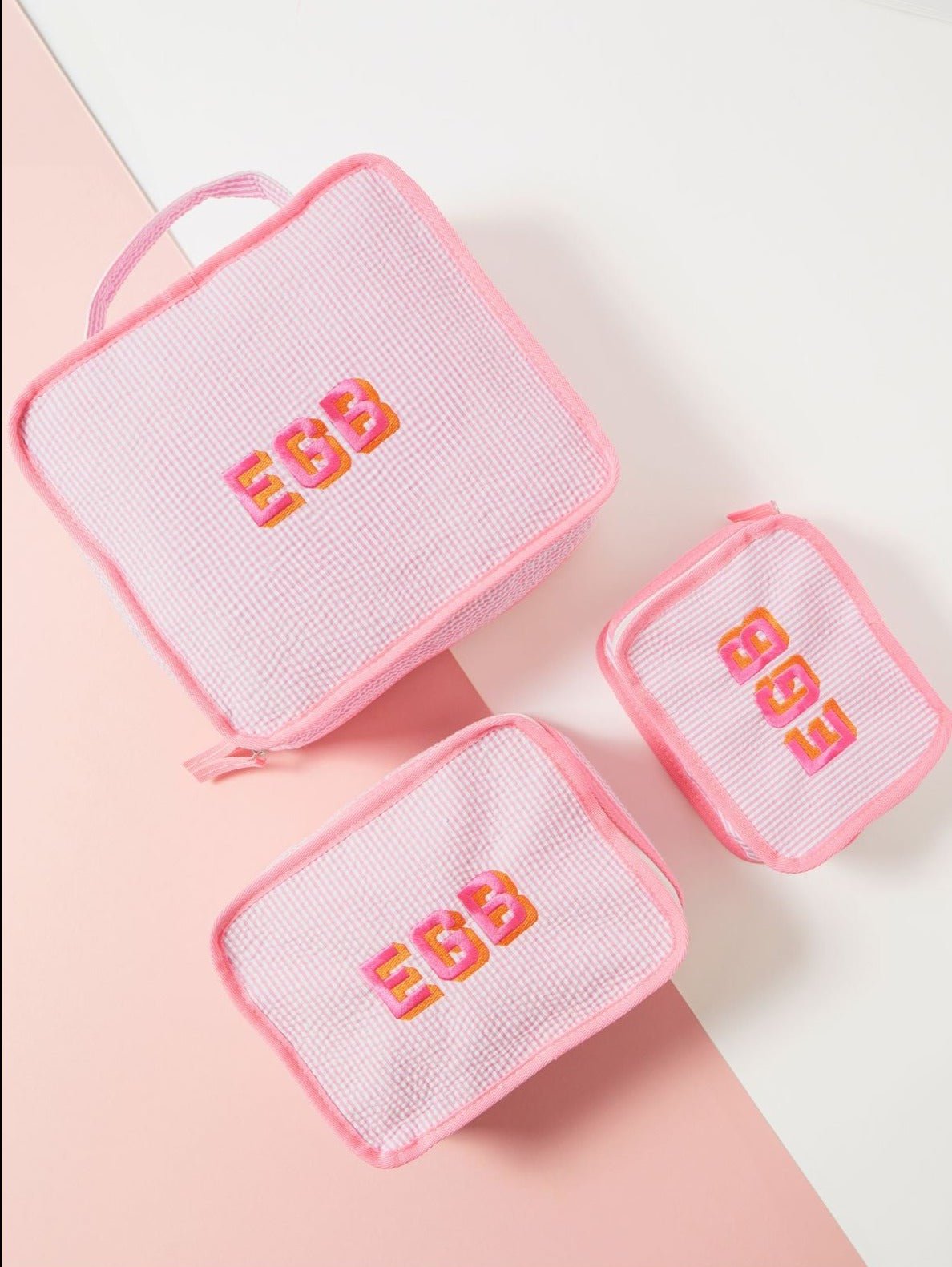 Three pink striped pouches all monogrammed with 'EGB'