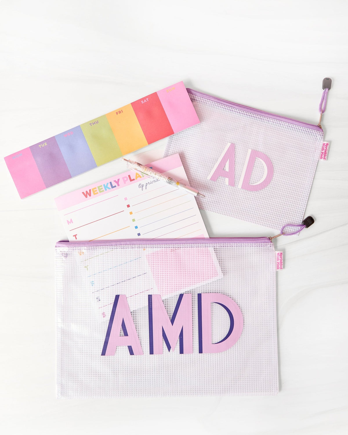 Two clear pool bags with purple zippers and monograms: 'AD' in pink and 'AMD' in purple and pink.