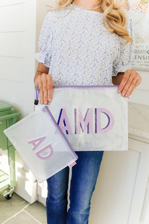 Two clear pouches with pink zippers and monograms in different sizes.